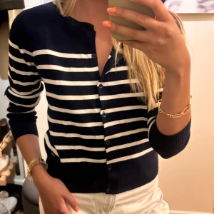 Marinblå randig kofta med knappar - Säljer en marinblå kofta med vita ränder och knäppning framtill. Super skönt material som andas! 