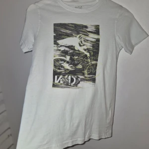 Warp boy Stadium t shirt storlek 134/140! - Vit t-shirt från H&M med ett stort svartvitt tryck av en cyklist på framsidan. T-shirten har rund halsringning och korta ärmar. Perfekt för dig som gillar sportiga motiv.                                                  Snygg Warp t shirt från Stadium med print framtill! Storlek 134/140 Fint använt skick!  Djur och rökfritt hem