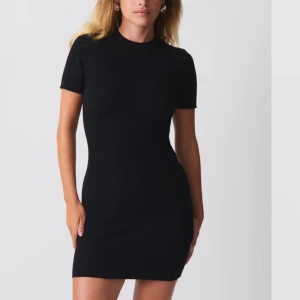 Svart ribbad kortklänning - En svart ribbad kortklänning med tight passform och korta ärmar. Klänningen har en enkel och stilren design som passar perfekt till många olika tillfällen. Materialet är stretchigt och följsamt för en bekväm känsla. Nypris 400