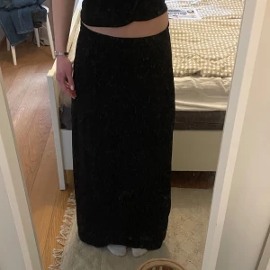 Svart långkjol från ICHI - Säljer en svart långkjol från ICHI. Kjolen har en rak och enkel design utan synliga detaljer eller mönster, vilket gör den stilren och lätt att matcha. Den har ett skönt och härligt material perfekt till sommaren.