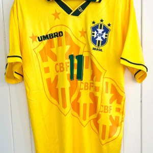 Romario - Brasilien VM 1994 - Säljer en klassisk fotbollströja, Romarios matchtröja från VM 1994 när hans Brasilien vann över Italien och blev världsmästare. Tröjan är en remake i nyskick. Aldrig använd.  Large, normal i storleken.  Skickas inom 24 h.  #fotboll