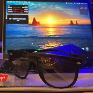 Svarta Ray-Ban Boyfriend - Klassiska svarta solglasögon från Ray-Ban med Wayfarer-inspirerad form. Glasögonen har svarta bågar i plast och mörka linser. Ray-Ban-loggan syns tydligt på skalmen och linsen. Perfekt accessoar för soliga dagar. ÄKTA, kvitto och äkthetsbevis finns