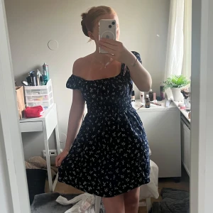 Mörkblå blommig klänning från Cotton:On - Supersöt mörkblå kortklänning från Cotton:On med små vita blommor. Klänningen har resår i midjan, korta puffärmar och en söt offshoulder-modell. Perfekt för varma dagar och ger en romantisk vibe. Den är bara andvänd ett fåtal gånger! Ifall du har fler frågor eller vill se fler bilder är det bara att höra av sig!💛