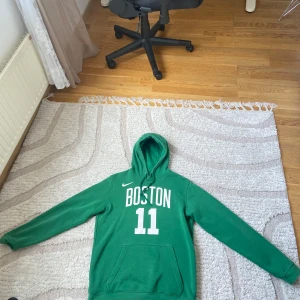 Grön Boston Celtics hoodie med nummer 11 - Säljer en grön Boston Celtics hoodie från Nike med tryck 'BOSTON 11' på framsidan och 'IRVING 11' på ryggen. Klassisk känguruficka och huva. Perfekt för basketfans som vill visa sitt stöd för laget. Sällsynt tröja 