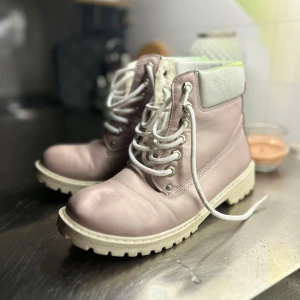 Skor - Säljer ett par ljusrosa boots med vit, grov sula och vit snörning. Skorna har en vadderad, ljus krage upptill. Fodrade. Nästan helt nya 