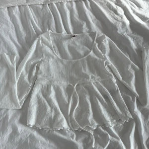 Vit långärmad topp med knyt i midjan - Säljer en söt vit långärmad topp med rundad urringning och knytband i midjan. Toppen har lätt rynkad struktur och volangkant nertill. Aldrig använt enbart provat men tog bort lappen så kan inte lämna tillbaka. Pris går även att diskutera men köpte toppen för 200❤️