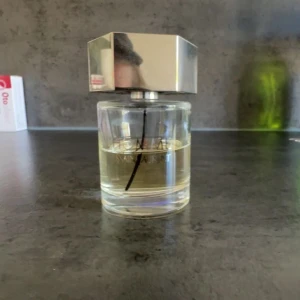 Yves Saint Laurent L'Homme EdT - Säljer en flaska L'Homme Eau de Toilette från Yves Saint Laurent. Parfymen kommer i en genomskinlig glasflaska med en sexkantig, silverfärgad metallkork med YSL-loggan på toppen. Doften är fräsch och maskulin.