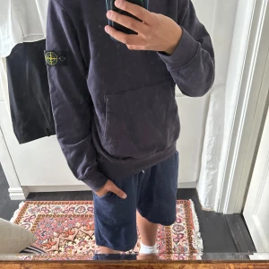 Mörklila hoodie från Stone Island - Säljer en lila hoodie från Stone Island med klassisk patch på vänster ärm. Tröjan har en stor magficka och långa ärmar. Perfekt för en avslappnad stil och enkel att matcha med det mesta. Riktigt skön