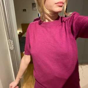 Mörkrosa stickad topp från Saint Tropez - Säljer en mörkrosa stickad topp från Saint Tropez. Modellen har korta puffärmar och ribbade kanter vid hals, ärmslut och nederkant. Perfekt för dig som vill ha en färgklick i garderoben!