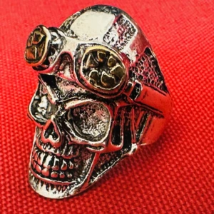 Biker / Steampunkring med dödskalle och gulddetaljer - Tung och detaljerad dödskallering i justerbar storlek med steampunkkänsla. Tillverkad i metall med silvrig finish och glasögon i guldfärgad metall. Perfekt för dig som gillar alternativ stil, rock eller bikerestetik – ett riktigt statement. Material: Troligen zinklegering Storlek: Justerbar Skick: Bra begagnat skick Prutning accepteras inte, men jag erbjuder gärna rabatt vid köp av flera!  