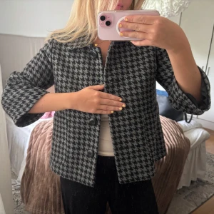Grå och svart mönstrad jacka från Lindex - Säljer en så fin jacka/kavaj aktig från Lindex i grått och svart mönster. Jackan har trekvartsärm, stora knappar framtill och en rak passform. 