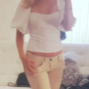 Vit topp med puffärm - Superfin vit topp med fyrkantig ringning och stora puffärmar. Sitter tight över kroppen och har en stilren, minimalistisk look. Perfekt för dig som gillar trendiga och feminina detaljer. Materialet känns mjukt och stretchigt. Xs-s💕