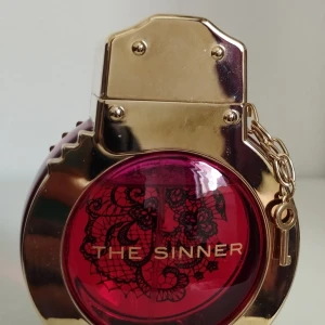 Police The Sinner 50ml parfym - Unik parfym från Police, The Sinner som är en minst sagt s*xig doft! Flaskan är rund med guldiga detaljer och en djup röd mitt med svart spetsmönster. Locket är guldfärgat och pryds av en liten kedja med nyckel. Flaskan har en edgy och lyxig design som sticker ut i samlingen. Enligt kommentarer på websidan Fragrantica påminner den om Muglers Alien.