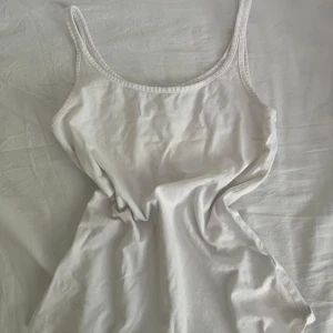 Vit linnetopp från Lindex XS - Enkel och stilren vit linnetopp från Lindex i storlek XS. Toppen har smala axelband och rundad halsringning, perfekt att matcha med jeans eller kjol. 