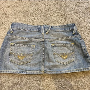 Jeanskjol med broderingar - Snygg blå jeanskjol med klassisk femficksdesign och broderade hjärtan i gult på bakfickorna, perfekt till sommaren! Obs: inte mina bilder (köpte kjoen här på plick, dessvärre passade den inte mig)