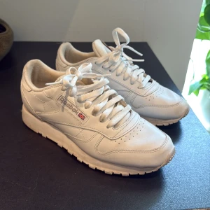 Vita Reebok Classic sneakers i skinn - Snygga vita Reebok Classic sneakers i skinn med ikonisk logga på sidan och häl. Inte speciellt använda och ser nya ut på utsidan. Nypris ca 950