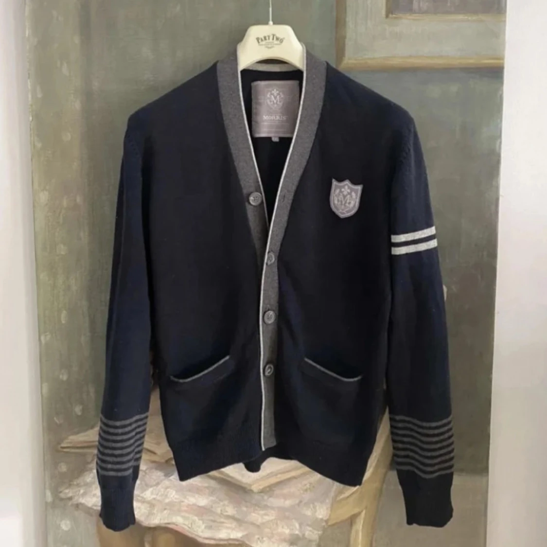 Mörkblå kofta med grå detaljer och emblem