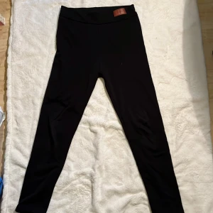 Svarta fleecefodrade leggings - Svarta leggings med mjukt fleecefoder på insidan som håller dig varm. De har en hög midja och är stretchiga för en bekväm passform. Perfekta för kyligare dagar när du vill vara både snygg och varm.