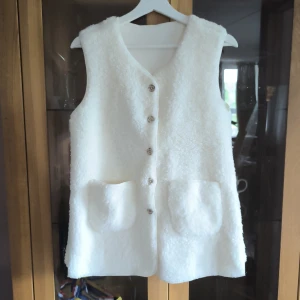 Vit väst från SHEIN - Mysig vit teddyväst från SHEIN med knappar framtill och två stora fickor. Västen har en rak passform och är tillverkad i ett fluffigt syntetmaterial som ger en trendig look. Väldigt mjuk och skön. Aldrig använt den bara provat.
