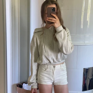 Ljusgrå croppad hoodie - Säljer en ljusgrå croppad hoodie med huva och dragsnören. Tröjan har långa ärmar och bred resår i midjan samt vid ärmsluten. Bra material och mjuk på insidan. STOR luva, jätteskön :))