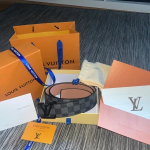 Louis Vuitton Damier Graphite bälte - Säljer ett Louis Vuitton bälte i klassiskt Damier Graphite-mönster med svart LV-spänne. Bältet är svart och grått, tillverkat i skinn och levereras med originalförpackning, dustbag och kvitto. Priset kan diskuteras 