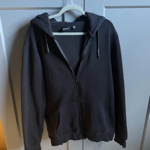 Svart hoodie med dragkedja från Only & Sons - Säljer en svart hoodie från Only & Sons med dragkedja och huva. Den har långa ärmar och snörning vid huvan. Perfekt för en stilren look. Helt oanvänd! Bara höra av sig vid frågor!