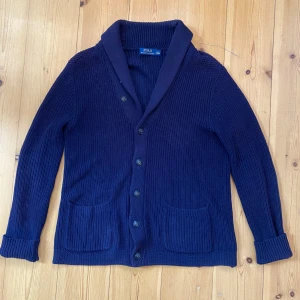 Kofta / Cardigan Polo Ralph Lauren - En unik stickad cardigan/kofta från Polo ralph lauren i mörkblå färg. Koftan är i storlek small men sitter som en större medium beroende på hur man vill att den ska sitta.  Tveka inte att skriva vid frågor!