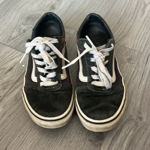 Svarta sneakers från Vans - Säljer ett par klassiska svarta Vans sneakers med vit sula och snörning. Skorna har den ikoniska vita sidostripen och 'Off the Wall'-logga på hälen. 