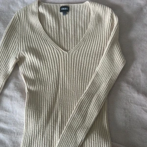 Beige ribbad tröja från RYVLS - Säljer en stilren beige ribbad tröja från RYVLS.  köpt från kidsbrandstore. Tröjan har en v-ringad design och långa ärmar, perfekt för en elegant och bekväm look. Passar utmärkt till både vardag och mer uppklädda tillfällen.
