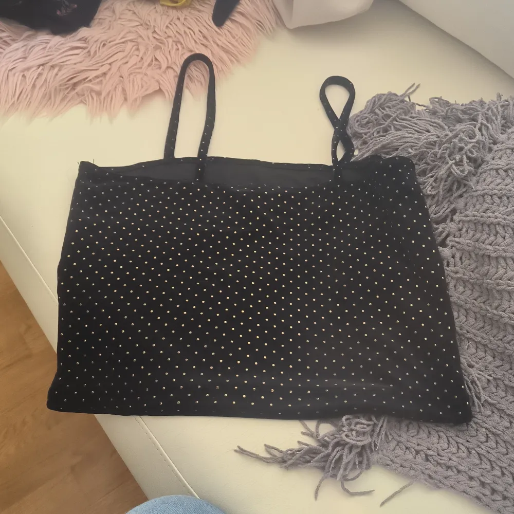 Säljer en svart linnetopp från Bik Bok med små guldprickar. Toppen har smala axelband och är perfekt för en stilren look. Passar bra till både jeans och kjol. Storlek S men passar även M. . Yläosat.