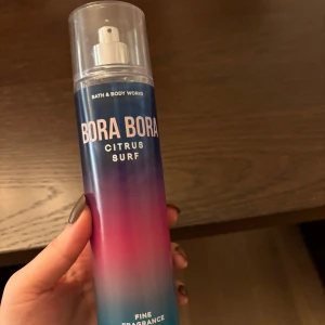 Bora Bora Citrus Surf från Bath & Body Works - Fräsch och uppfriskande doftspray från Bath & Body Works med namnet Bora Bora Citrus Surf. Flaskan har en gradientdesign i blått, lila och rosa som ger en tropisk känsla. Perfekt för att ge en somrig och citrusdoftande upplevelse.
