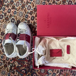 Valentino Garavani sneakers i rött och vitt - Snygga röda Valentino Garavani sneakers. Köptes begagnat här på plick men kvitto, låda och dustbag finns! Märkbart slitna därav priset, mycket av smutsen går säkert att tvätta bort!🩷