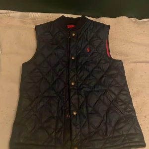 Svart quiltad väst från Polo Ralph Lauren - Snygg mörkblå väst från ralphlauren som är perfekt nu för våren, pris kan diskuteras! Passar om du är 170-180
