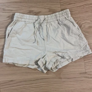 Beige shorts med resårmidja - Snygga och bekväma beige shorts med resårmidja och dragsko. Perfekta för en avslappnad stil. De har praktiska sidofickor och är gjorda i ett lätt material. Storlek: 158