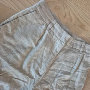 Beige linnebyxor från H&M, nästan nya! - Snygga beige linnebyxor från H&M med en avslappnad passform. Perfekta för varma dagar med sin lätta och luftiga känsla. Byxorna har en klassisk design med fickor och bälteshällor. Endast använd en gång, tyvärr lite skrynklig då den följt med i en flytt.