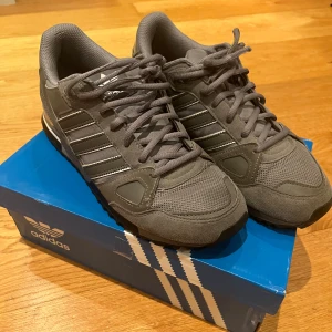 Grå Adidas ZX 750 sneakers - Snygga grå Adidas ZX 750 i mycket gott skick. Så gott som nya! Sparsamt använda. Strl 42. Orginal kartong finns