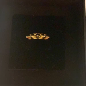 Guldfärgad ring med nitar!❤️ Edblad - Snygg guldfärgad ring med spetsiga nitar som ger en edgy look. Perfekt för att lägga till lite attityd till din stil. Ringen har en slät yta på insidan för bekväm passform.