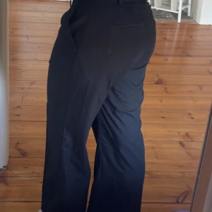 Svarta kostymbyxor från Gina Tricot - Snygga svarta kostymbyxor från Gina Tricot i storlek M.  Låg/mid midja och raka ben. Uppsydda till ca 70 cm innerbenslängd