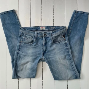 Replay Anbass - Snygga ljusblå jeans från Replay i modellen Anbass. De har en klassisk femficksdesign och en knappgylf. Perfekta för en avslappnad stil. Fint skick förutom att de är ett hål bak på byxorna men de är knappt så att man ser förutom om man inte kollar extra noga!