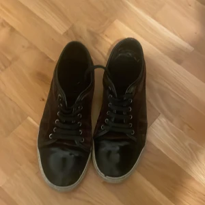 Svarta sneakers från Lanvin - Snygga svarta sneakers från Lanvin med snörning och en glansig finish. Skorna har en robust sula och en klassisk design som passar perfekt för en stilren look.