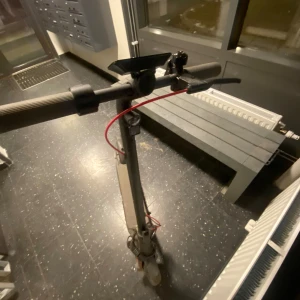 Grå elscooter med röd kabel åker i 60km ifall man trimmar  - Säljer en grå elscooter med en röd kabel vid styret. Scootern har en svart plattform och handtag, samt en kombinationslås runt styret. Perfekt för smidig transport i stan! Och åker i 60km ifall man trimmar den med Appen!!!