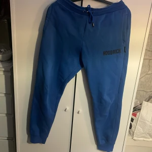 Blå mjukisbyxor från Hoodrich - Säljer ett par blå mjukisbyxor från Hoodrich i storlek medium. Byxorna har en normal passform med snörning i midjan och en diskret logga på sidan. 