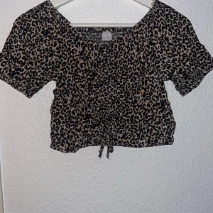 Leopardmönstrad kortärmad topp från Index - Säljer en leopardmönstrad kortärmad topp från Index. Toppen har en snygg knytning framtill och är perfekt för en trendig look. Passar storlek 158/164. Man får en enorm snygg form.