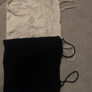 Svart och vit linnetopp från Gina Tricot - Säljer två stilrena linnetoppar från Gina Tricot i svart och vitt. Perfekta för lager-på-lager eller att bära som de är. De har smala axelband och en enkel design som passar till det mesta. Väldigt korta linnen, långa band. Banden kan man lägga in i linnet så blir de som en topp utan band. Passar till allting.