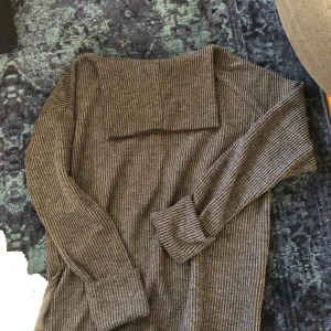 Grå ribbad tröja från Hailys - Säljer en stilren grå ribbad tröja från Hailys. Tröjan har långa ärmar och en bekväm passform, perfekt för kyligare dagar. Den ribbade strukturen ger en snygg detalj till din outfit. Passar bra till både jeans och kjol.