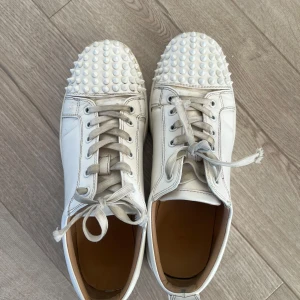 Vita louboutin  - Vita louboutin klassisk röd sula. Skorna har snörning och är tillverkade i skinn, vilket ger en lyxig känsla. Perfekta för dig som gillar vita matchande skor. 42 i storlek och priset går att diskutera 