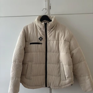 Beige pufferjacka från FB Sister - Perfekt för kyliga dagar! Ny med prislapp och luva.