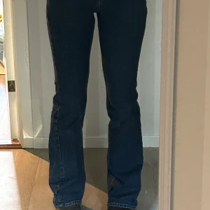 Mörkblå jeans från Gina Tricot  - Säljer ett par mörkblå jeans från Gina Tricot. De har en klassisk design med en bootcut-stil och är hög midjade, är tillverkade i jeansmaterial. Perfekta för en avslappnad look.