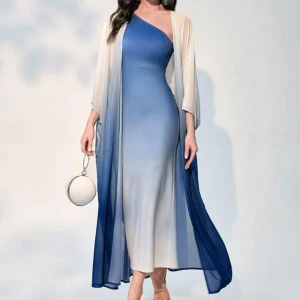 Blå one-shoulder klänning med kofta SETT - Elegant blå SET långklänning med en one-shoulder design och vacker ombre-effekt som går från ljus till mörk blå. Klänningen har en luftig, transparent överdel som ger en extra dimension till looken. Perfekt för en stilfull kväll. 