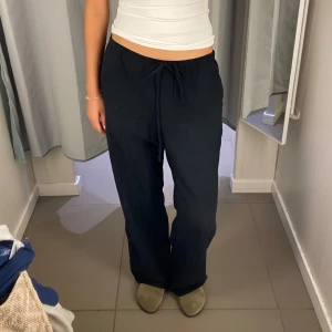 Svarta Low waist linnebyxor - Säljer ett par bekväma linnebyxor från H&M i storlek M. Dessa byxor har en avslappnad passform och dragsko i midjan, vilket gör dem perfekta för både vardagsbruk och avslappnade tillfällen. Det lätta materialet gör dem idealiska för varmare dagar. Kombinera med en enkel t-shirt eller linne för en cool och avslappnad look! Mycket bra skick, sparsamt använda. Ingen synlig slitage.